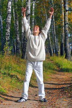 happy boy stand in autumn forest with hands up