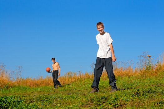 Happy teenagers play a ball on a field