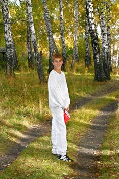 boy in autumn forest stand on the road