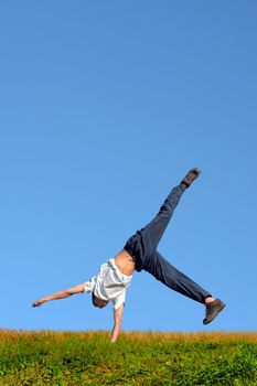 Somersault on grass on the blue sky background