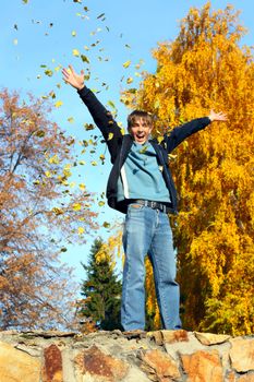 happy teenager scatter leafs in the autumn park