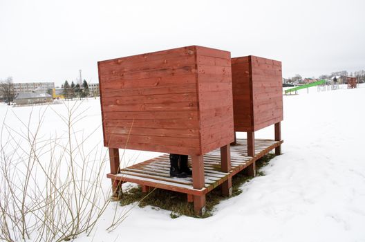 lake beach plage dressing changing cabin booth surrounded by snow and woman legs with hot leather shoes in winter.