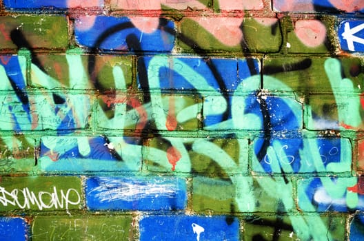 colorful painted brick wall with notes and marks of vandalism. urban background.