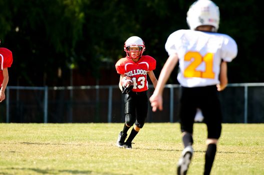 Youth football boy running the ball.