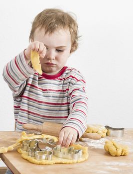young child working with dough on wooden desk with flour. Vertical image