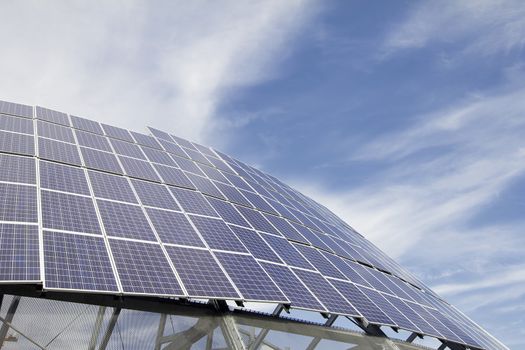 Group of Solar Panel Modules Against Blue Sky with Clouds