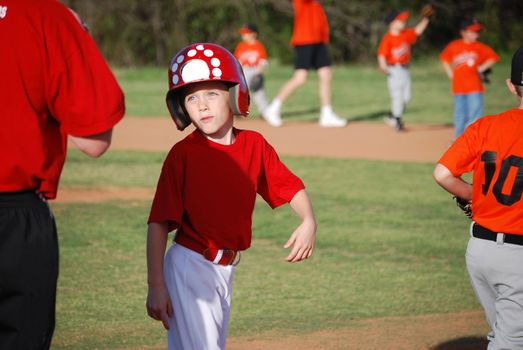 Cute baseball little league player smiling at coach.