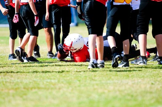 Tackled football boy in the middle of a group of players.