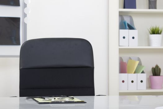 Doctor office table desk and black chair with stethoscope  and white paper