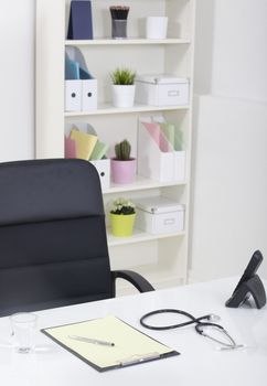 Doctor office table desk and black chair with stethoscope  and white paper