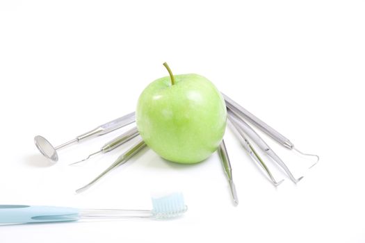 Green apple and dental tools isolated on white