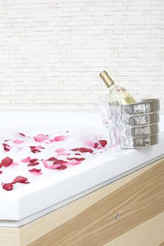 A relaxing bath with rose petals ,wine and glassess