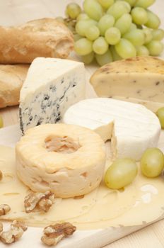Various Types of Cheese and Grapes on Wooden Chopping Board 