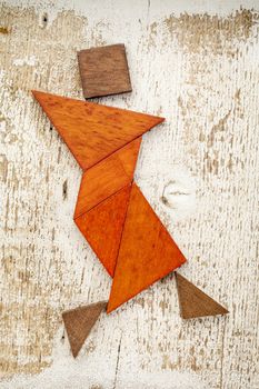 abstract figure of a female dancer built from seven tangram wooden pieces, a traditional Chinese puzzle game; rough white painted barn wood background