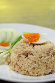 close up  fried rice with pork and boiled egg served with fresh vegetable on white dish