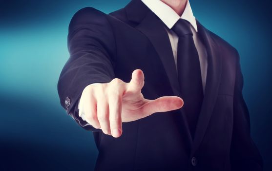 Business man with pointing to something or touching a touch screen on blue background