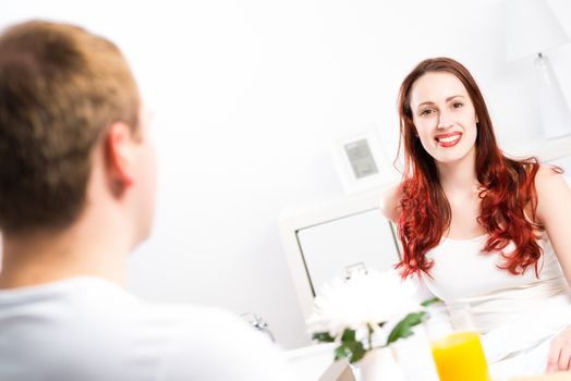 man brought his girlfriend breakfast in bed, holding a tray of juice and breakfast