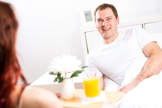 woman brought her boyfriend breakfast in bed, holding a tray of juice and breakfast