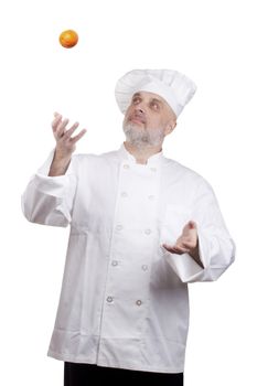 Male chef juggling oranges. Fun cooking. White background.