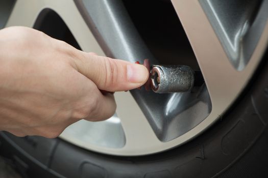 Hand fill air into a car tire.