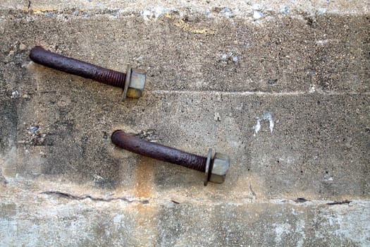 Two Rusty Bent Lag Bolt in Concrete.