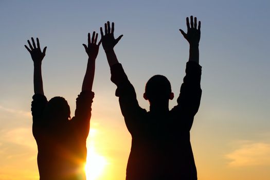 young couple hands up silhouette