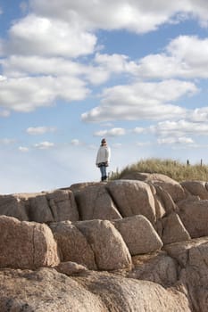 woman looking out to sea at the top of old natural rock formation on a beach in county Donegal, Ireland