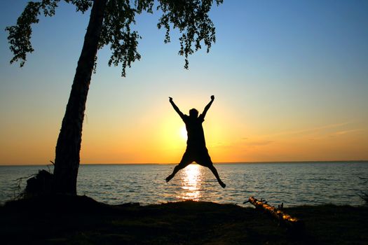 happy person jumping on the sunset sky background