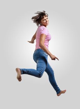 pretty modern slim hip-hop style woman jumping dancing on a grey background