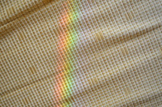 artificial rainbow light on yellow fabric background.