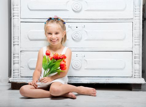 little girl with a bouquet of flowers sitting on the floor