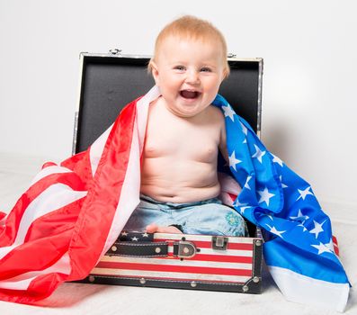 smiling cute baby in a suitcase with American flag