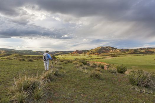 male hiker with a backpack contemplates sunset over Red Mountain Open Space near Fort Collins, spring scenery