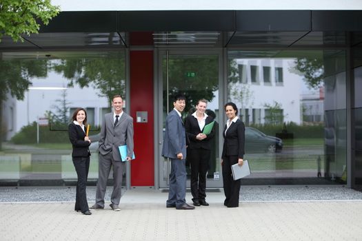 Group of diverse multiethnic business colleagues in suits standing posing outside the entrance to the office