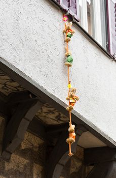 Funny photo of four small stuffed bears and toys climbing down a rope suspended from window of old half-timbered house
