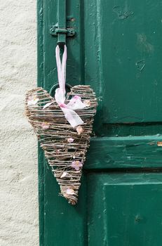 German tradition of hanging a woven decoration onto a front door of house in shape of a heart with ribbon