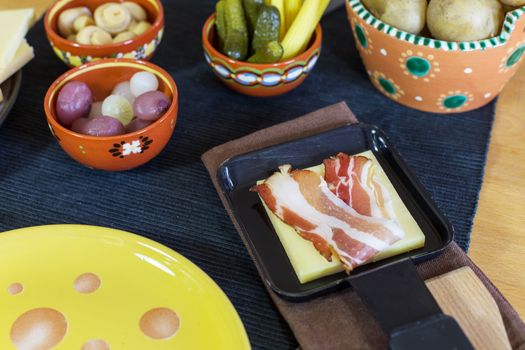 Swiss raclette, traditional specialty of grilled yellow cheese, potatoes and pickles.