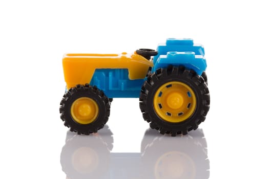 Small plastic tractor toy isolated on white background close up.