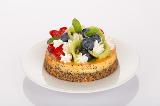 Cheesecake with strawberry, blueberry, kiwi and cream on white plate.