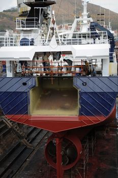 Ship in dry dock for repairing and painting. View over the stern and screw propeller. 