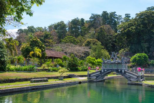 Green park with clean lake and stone balinese style arch bridge, Tirtaganga, Bali