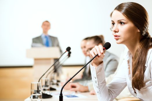 Business woman speaks into a microphone, communication businessmen at a conference