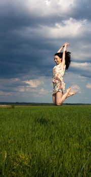 young girl jumping on the field on sunny summer day