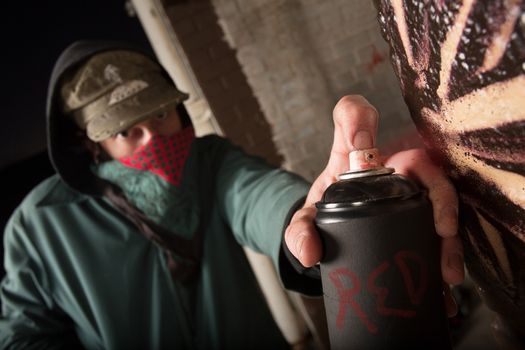 Black spray paint can held by anonymous criminal