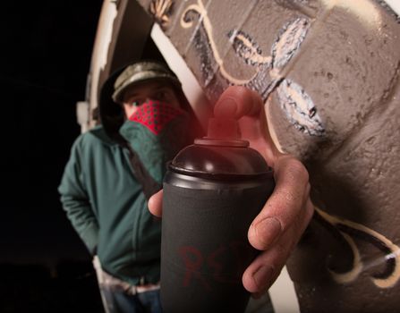 Man with hood and face covering holding spray paint can