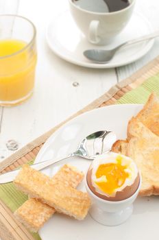Breakfast items including boiled egg, toast, coffee and orange juice