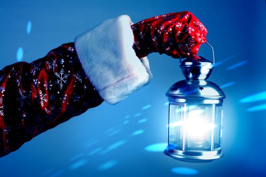 The hand of Santa Claus holds a lamp