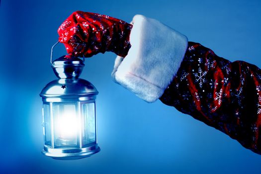 The hand of Santa Claus holds a lamp