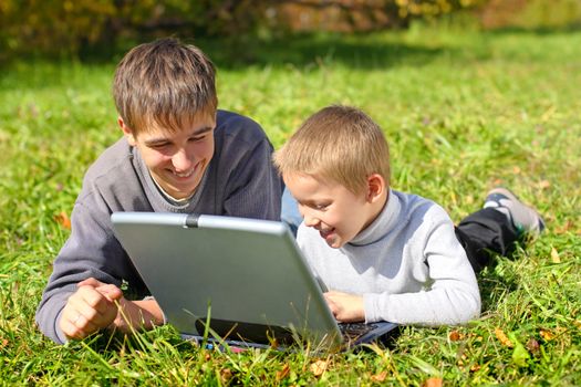 teenager and kid with notebook on the meadow