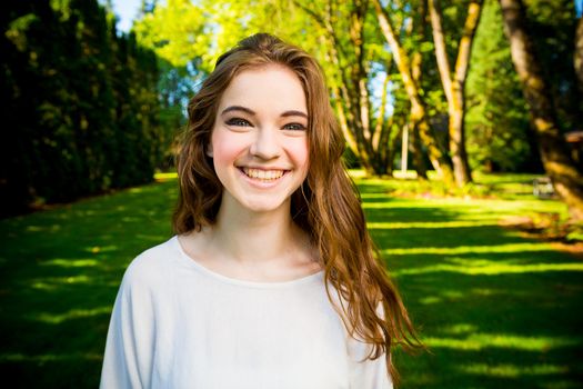 A beautiful young girl poses for a fashion style portrait outdoors at a park with natural lighting.